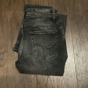 Svarta jeans från Jack & Jones - Snygga svarta jeans från Jack & Jones med en cool tvättad look. De har en klassisk femficksdesign och en bekväm passform. Perfekta för en stilren vardagslook. Hör av er vid frågor! Inte spikat pris!