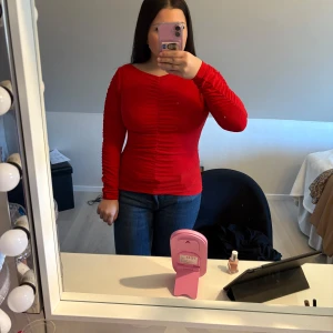 Röd långärmad topp från Lindex - Säljer en snygg röd långärmad topp från Lindex. Toppen har en åtsittande passform med rynkade detaljer framtill som är en fin detalj.