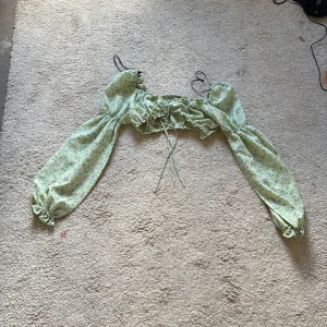 Grön blommig offshoulder-top - Säljer en söt grön offshoulder-top med blommigt mönster. 
