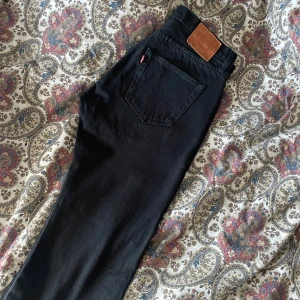 Svarta jeansbyxor från Levis - Säljer ett par svarta 501 jeans från Levis för män. De har en rak passform och är perfekta för en stilren look. Storlek W33 och L30