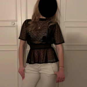 Svart transparent blus med prickar - Säljer en elegant svart transparent blus med prickigt mönster. Blusen har korta ärmar och en volangdetalj i midjan som ger en fin siluett. Perfekt för en stilfull look.❤️skriv vid frågor eller funderingar