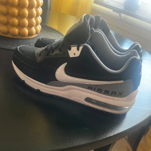 Svarta Nike Air Max sneakers - Snygga svarta Nike Air Max sneakers med vit sula och klassisk Air Max-dämpning. Skorna har en vit Nike-logga på sidan och snörning framtill. Perfekta för både vardag och träning.