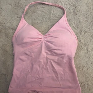 Rosa linnetopp från DFYNE - Säljer en söt rosa linnetopp från DFYNE med halterneck-design och rynkdetalj framtill. Perfekt för varma sommardagar eller träning. Toppen har en smickrande passform och är gjord i ett mjukt material. Slutsåld på hemsidan! Använd 1 gång. Kvitto finns