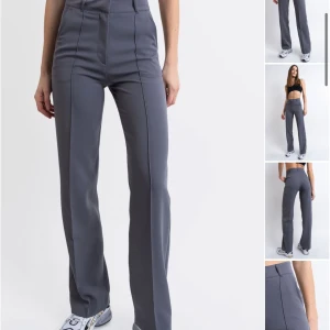 Grå kostymbyxor från Madlady - Snygga grå kostymbyxor i modellen Nova02 High från Madlady med en klassisk rak passform. Byxorna har en stilren design med hällor för bälte och en diskret dragkedja. Perfekta för en elegant look. 