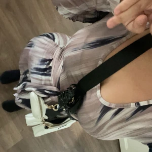 Mönstrad långklänning med knytband - Snygg långklänning med abstrakt mönster i beige och svart. Klänningen har långa ärmar och ett knytband i midjan för en smickrande passform. Perfekt för en stilfull look. Använt den 3 gånger det står tyvärr inte vart den är ifrån men tror den e från shein.