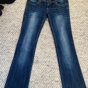 Blå jeans från Replay - Snygga blå äkta y2k bootcut jeans från Revers med en klassisk femficksdesign och dubbla knappar i midjan. 