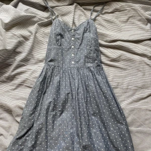 Ljusblå somrig klänning - En jättesöt somrig klänning med små vita stjärnor och vita knappar på framsidan. Köpt för länge sedan så jag minns inte var den är ifrån. Skulle säga att storleken är mer åt small än medium.