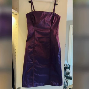 Lila miniklänning - Snygg lila axelbandslös klänning med dragkedja bak. Perfekt för en kväll ute eller en speciell tillställning. Banden går att ta på och av.