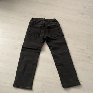 Svarta byxor från Lindex - Säljer ett par svarta byxor från Lindex i storlek EUR 140. Byxorna har en elastisk midja och raka ben. Perfekta för en avslappnad stil.Längd på byxorna är 81cm