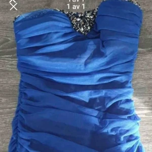 Blå axelbandslös klänning - Snygg blå axelbandslös klänning med glittriga detaljer upptill. Klänningen har en draperad design som ger en elegant look. Perfekt för festliga tillfällen.