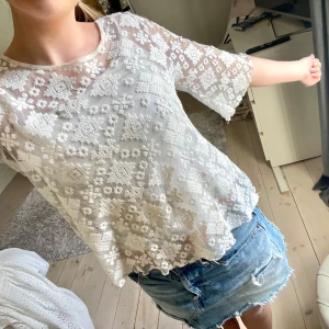 Vit spetsblus - Säljer en söt vit spetsblus med trekvartsärmar och ett vackert blommigt mönster. Perfekt för en somrig look! Har ett linne under på denna bild!