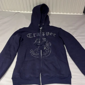 Mörkblå zip hoode med rhinestones - ‼️BILLIGARE VID SNABB AFFÄR‼️Fet zip up från Crapper med rhinestones på. Tröjan är oanvänd alla rhinestones sitter kvar 10/10 skick. Stl M 