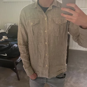 Beige långärmad skjorta - Säljer en stilren beige långärmad skjorta, perfekt för sommaren. Använd ett par gånger men fortfarande väldigt bra skick utan några defekter. Skriv om ni har några frågor!