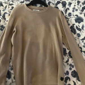 Beige tröja från Jack & Jones - Säljer en stilren beige tröja från Jack & Jones. Tröjan har en ribbad struktur och långa ärmar, perfekt för en avslappnad look. Passar bra till både jeans och chinos.