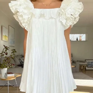 Vit plisserad klänning med volang - Superfin vit kortklänning med plisserat tyg och stora volangärmar. Väldigt populär och eftertraktad! Perfekt för sommarens alla tillfällen. 