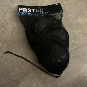 Svarta skyddshandskar PRST50 Small - Skyddshandskar från PRST50 i svart med hårda skal och justerbara kardborreband. Perfekta för inlines, skateboard eller scooter. Säljs i set med handledsskydd, armbågsskydd och knäskydd. Snygg och sportig design som ger bra skydd vid actionfyllda aktiviteter.