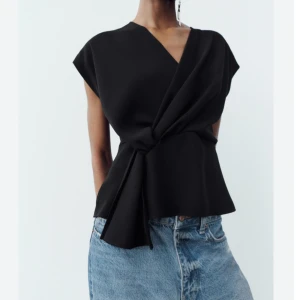 Svart omlottopp med knyt🖤 - Säljer en svart omlottopp med stilren knytning i midjan och v-ringad hals. Toppen har korta ärmar och en lite lös passform som ger en snygg siluett. Perfekt att styla till vardagen, passar storlekarna från s-m 🖤 kontakta mig vid frågor, jag svarar så fort jag kan.