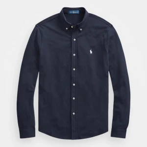 Mörkblå skjorta från Ralph Lauren - Snygg svart långärmad skjorta från Ralph Lauren med klassisk krage och vita knappar. Skjortan har en broderad logotyp på bröstet och är tillverkad i ett lättviktigt material. Perfekt för en stilren look.