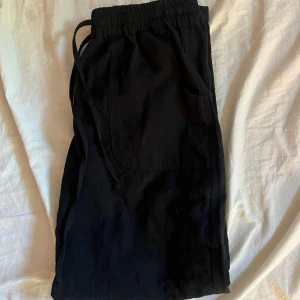 Svarta linnebyxor med snörning - Svarta linnebyxor med resår i midjan och snörning. Byxorna har stora fickor framtill. Dom är jätte snygga