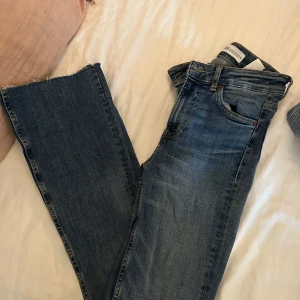 Blå jeans med rå kant från Zara bootcut full längd och hög midja - Snygga blå jeans från Zara med rå, fransad kant nertill. Klassisk femficksmodell i denim med lätt tvättad look. Normal passform och midja, perfekta till sneakers eller boots.