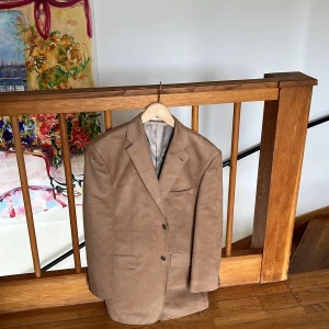 Beige mockakavaj från Atlant - Snygg beige kavaj i mocka från Atlant. Klassisk modell med två knappar framtill, tre fickor och slät baksida. Fodrad insida i ljusgrått tyg. Perfekt för dig som vill ha en stilren kavaj nu i sommar. Storlek 52