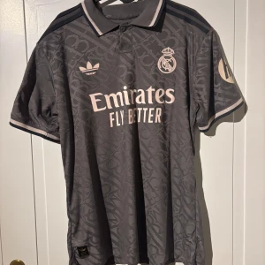 Real Madrid Tredje Tröja - Säljer min Real Madrid tredje tröja med Mbappe #9 där bak och UCL och HP badgerna på sidan. Har aldrig använt den utan den har suttit i min garderob hela tiden. Storleken är XL men den är mindre i storlek så de är mer som L för de är Autentisk Spelar tröja. Vid frågor är det bara att skriva.