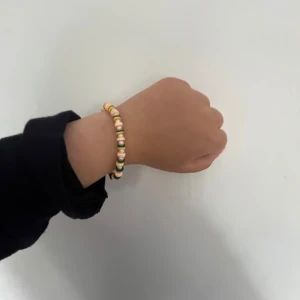 Färgglatt pärlarmband med gulddetaljer - Säljer ett handgjort armband med små runda pärlor i vitt, gult, grönt och rosa. Armbandet har en enkel kedja och lås i guld- eller silverfärg. Perfekt accessoar för att liva upp din outfit med lite färg och lekfull stil. Det finns 1 i guld och en i silver.