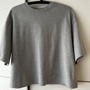 COS  t-shirt i grå bomull - En oversized t-shirt grå tjock bomull från COS. Använd 1 gång. Jag köpte flera färger i samma model och den gråa använder aldrig. Köpt i London för 500kr. Säljer för 300kr storlek S men mer som M