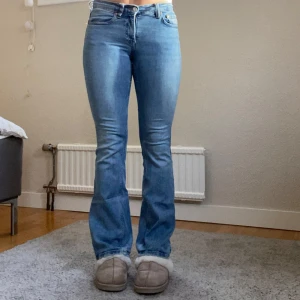 Ljusblå bootcut jeans från Gina Tricot - Säljer ett par ljusblå bootcut jeans från Gina Tricot. Jeansen har klassisk femficksdesign, normal passform och är tillverkade i mjukt denimtyg. Snyggt utsvängda ben och midwaist. Perfekta till sneakers eller boots. Bruna lappen på baksidan är lite söndrig men inget som egentligen påverkar byxan. Storlek 34.