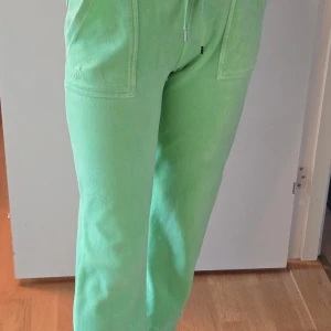 Mintgröna mjukisbyxor Juicy Couture S - Snygga mintgröna mjukisbyxor från Juicy Couture med raka ben, stora fickor fram och bakficka med knappar. Byxorna har dragsko i midjan och är gjorda i mjuk bomullsmix. Perfekta för chill dagar eller när du vill vara extra comfy. En metall skydd saknas för snoret annars I toppen skick sparsamt använda 