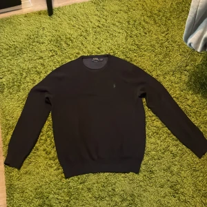 Svart tröja från Polo Ralph Lauren S-M - Klassisk svart tröja från Polo Ralph Lauren i storlek L (I barnstorlek) men är S-M i vuxenstorlek. Tillverkad i mjuk pima bomull med rund hals och diskret broderad logga på bröstet. Långärmad modell med ribbade muddar och nederkant. Perfekt för en clean och stilren look. 