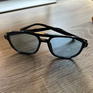Svarta retro pilotbågar glasögon - Snygga svarta glasögon med klassisk pilotform och dubbla bryggor. Bågarna är i blank plast och har en cool vintagekänsla. Perfekta för dig som vill sticka ut med en tidlös och trendig look.