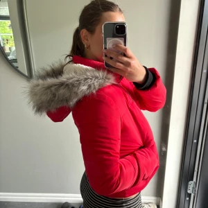 Jättensygg röd jacka - Knappt använd jacka. Otroligt fin röd färg och en stor bred luva med vitt vaddering. Storlek 13/14 år men passar mer som xs/s. Lite liten på mig som är 170 cm lång oxh vanligtvis har S/M i jacka. 