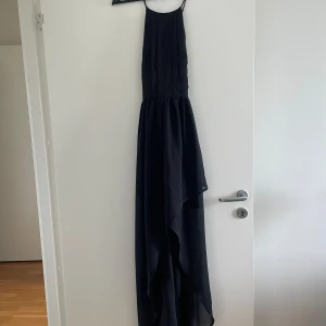 Svart långklänning Gina Tricot 34 - Snygg svart långklänning från Gina Tricot i storlek 34. Klänningen har tunna axelband, asymmetrisk nederkant och är tillverkad i lätt polyester. Perfekt för dig som vill ha en stilren och elegant look med flowig känsla.