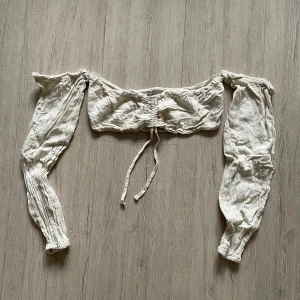 Beige offshoulder topp från Bershka - Beige offshoulder topp från Bershka med långa ärmar och knytning framtill. Knytningen går att dra ihop. Toppen är ca 10-15cm hög i tyget över bysten. Storlek S, och ingen stretch i materialet. 