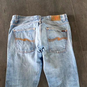 Feta Nudie Jeans 32x32 med mått🌟 - Säljer nu dessa feta Nudie jeans då de inte kommer till användning. Storleken är 32x34 men sitter som 32x32 (se mått på bilder). Skick 8.5/10,  på bild 5 syns slitning men det är slitning som ska vara så. Ända tecken av användning på jeansen är små slitningar på fickorna. Passformen är blanding mellan slim/skinny. Bara skriva om du vill ha mer bilder på jeansen kunde max  ladda upp 5 bilder🙌