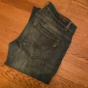 Blå jeans från Dondup - Snygga blå jeans från Dondup med en klassisk femficksdesign. De har en normal passform och är tillverkade i mjukt denim. Perfekta för en avslappnad stil. Jeansen är lagade i skrevet men ingenting som syns under användning. Passar 180-190cm