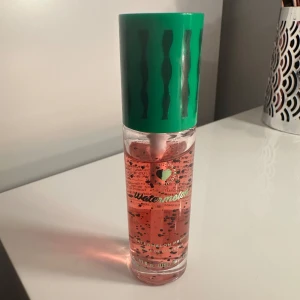 Vattenmelon Mist från Revolution - Fräsch och fruktig mist med doft av vattenmelon från Revolution. Flaskan är genomskinlig med rosa vätska och har ett grönt lock med mönster som påminner om en vattenmelon. Perfekt för en uppfriskande känsla under dagen.