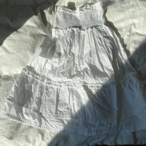Vit sommarklänning  - Vit sommarklänning med volang och detaljer, är en omsydd kjol o kan därför bli lite tajt, passar mindre storlekar ksk 34 / XS (har S/XS själv och passar men lite tajt), inga skavanker, lappen säger sisley 