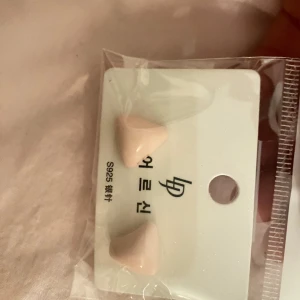 Rosa örhängen i trekantig form - Säljer ett par stilrena rosa örhängen i trekantig form. Perfekta för att ge en subtil färgklick till din outfit. De är små och diskreta, vilket gör dem lätta att bära till vardags.