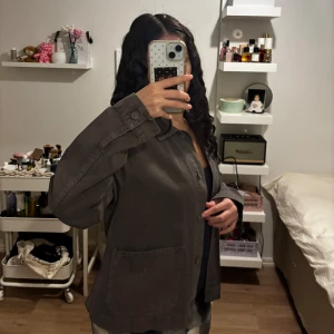 Grå/grön  jacka - Säljer en stilren jacka från pull n bear. Jackan har en klassisk krage och knäppning framtill. Den har långa ärmar och två praktiska fickor. Perfekt för en avslappnad look.