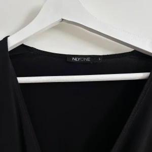Svart omlottklänning från NLY One - Elegant svart omlottklänning från NLY One med långa ärmar och v-ringad design. Perfekt för en stilren look.