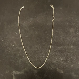 Silverfärgat halsband - Elegant silverfärgat halsband med en tvinnad design. Perfekt för att lägga till en subtil glans till din outfit. Passar bra till både vardag och festliga tillfällen.