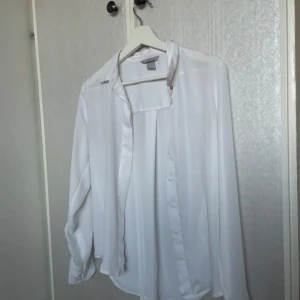 Vit blus från H&M - Säljer en stilren vit blus från H&M i storlek XS. Blusen har långa ärmar och knappar framtill. Perfekt för en elegant look💓