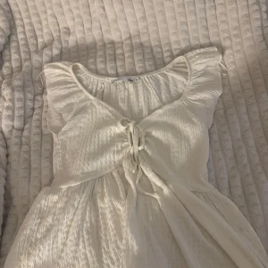 Vit blus från 157 - Säljer en söt vit blus från 157 med knytning framtill och volangdetaljer vid ärmarna. Perfekt för varma dagar. 💫 Aldrig användt😊