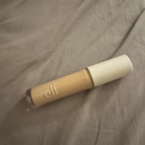 Concealer från e.l.f. - En concealer från e.l.f. i en ljus nyans. Perfekt för att täcka ojämnheter och ge en jämn hudton. Kommer i en praktisk tub med skruvlock.