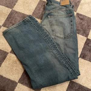 Blå jeans från Weekday - Säljer ett par blå jeans från Weekday i modellen Galaxy Loose Straight. De har en klassisk femficksdesign och en avslappnad passform. Perfekta för en casual look.