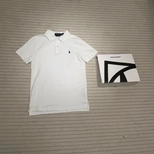 Vit pikétröja från Ralph Lauren (nytt skick) - Säljer en klassisk vit pikétröja från Ralph Lauren i slim fit perfekt nu när det börjar bli lite varmare. Tröjan är köpt för ungefär en månad sen men används ca 2 gånger. Ny pris ligger runt 1400. Skriv gärna om frågor eller fler bilder🙂