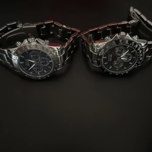 Svart och blå  klocka från Hugo Boss - Snygg och stilren klocka från Hugo Boss med silverfärgad länkarmband och blå urtavla. Klockan har tre mindre urtavlor och en tachymeter på ringen. Perfekt för den som vill ha en elegant accessoar.