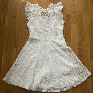 Vit spetsklänning - Vit klänning med öppen rygg, perfekt till studenten! Vet inte storleken men sitter som en S eller 36. Endast använd ett fåtal gånger. 
